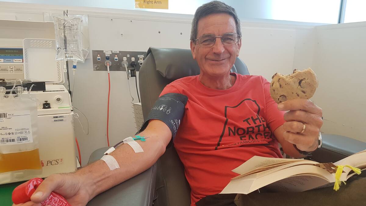 Relaxing read: Former Hastings Secondary School English teacher, Roger MacGibbon enjoys a cookee and book while giving blood.