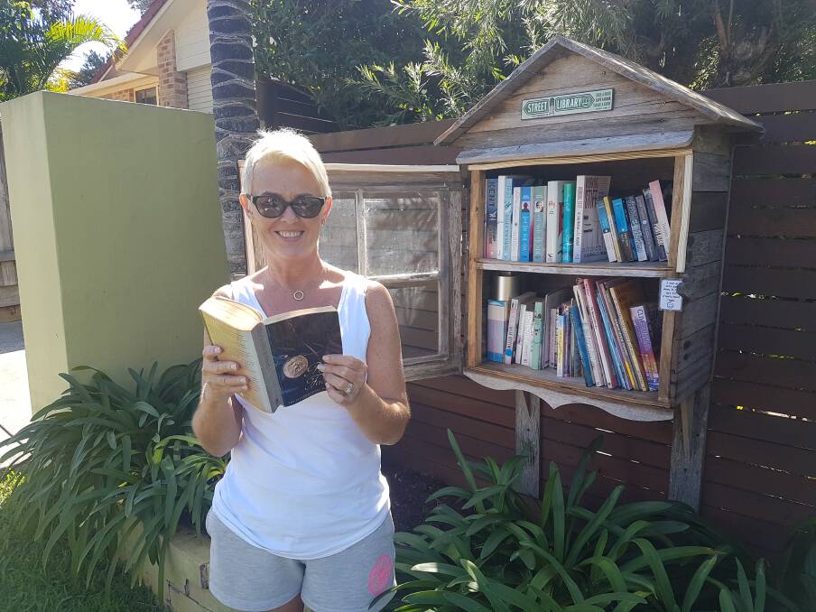 Ready to read: Newcastle visitor Gay Rogers at a street library in Swift Street, Port Macquarie.