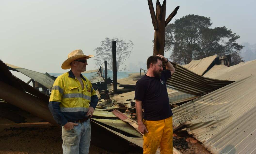 COUNTING THE COST: Brett Porter and one of his mill employees, Mat Oliver, check what's left after the fires. Photo: The Land/Jamie Brown.