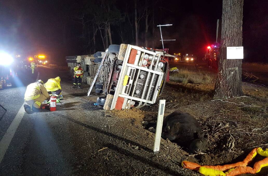 Into action: The truck laying on its side as crews get to work. Photo: Michael Ferguson.