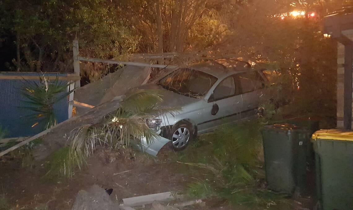 Wedged: The silver Ford station wagon among fence and trees that it struck.