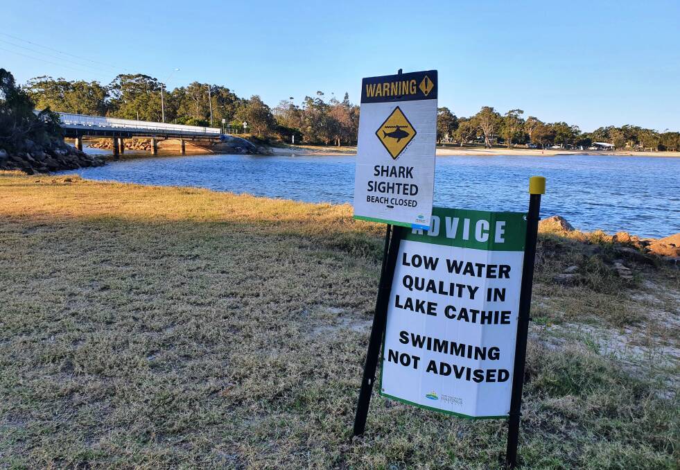 Take notice: Signs warn the public about the shark sighting as well as the low water quality in Lake Cathie.