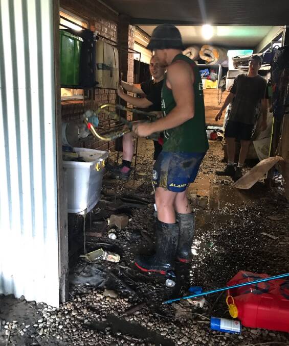 Pitching in: Port Macquarie Sharks players help to clean up after floodwater inundated the bottom level of Leonie Green's home on the North Shore.