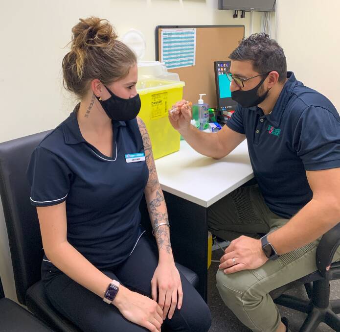 Line of defence: Your Discount Chemist Port Macquarie pharmacist Ibrahim Khodary (right) vaccinates Brittney McDonald against COVID-19. Photo: Your Discount Chemist Port Macquarie