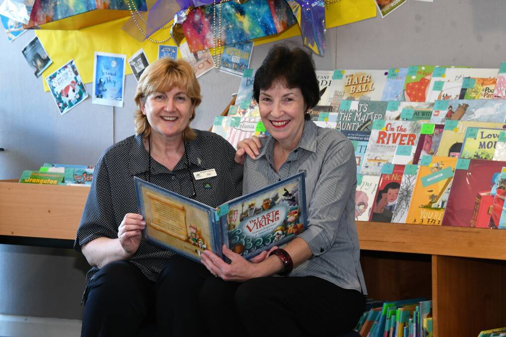 Library assistant Gail Wood and children’s/young adult librarian Virginia Cox appreciate one of the children's books.