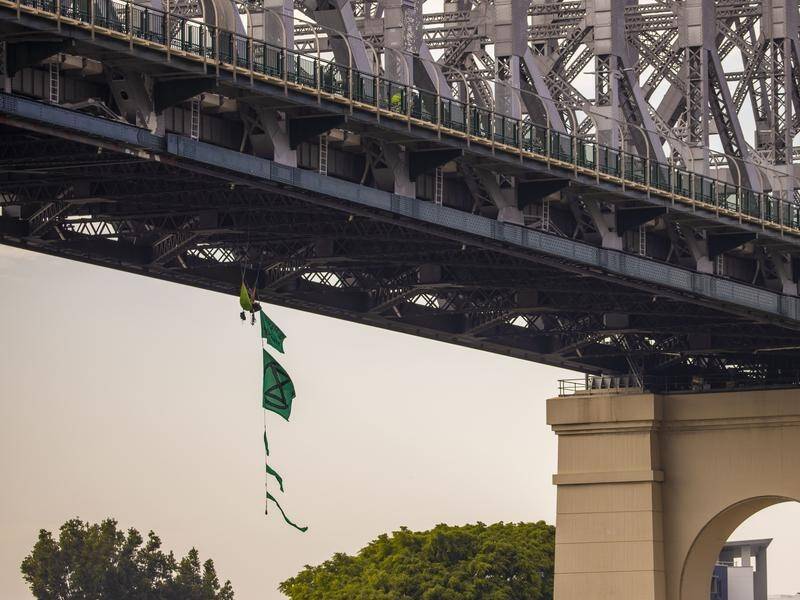 An activist from Extinction Rebellion dangles from the Story Bridge in a hammock in Brisbane.