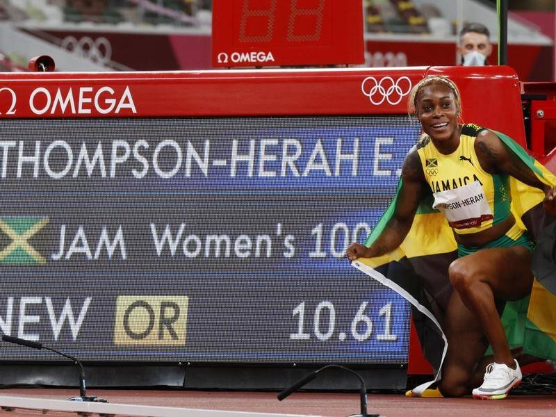 Elaine Thompson-Herah poses next to the scoreboard that recorded her latest Olympic triumph.