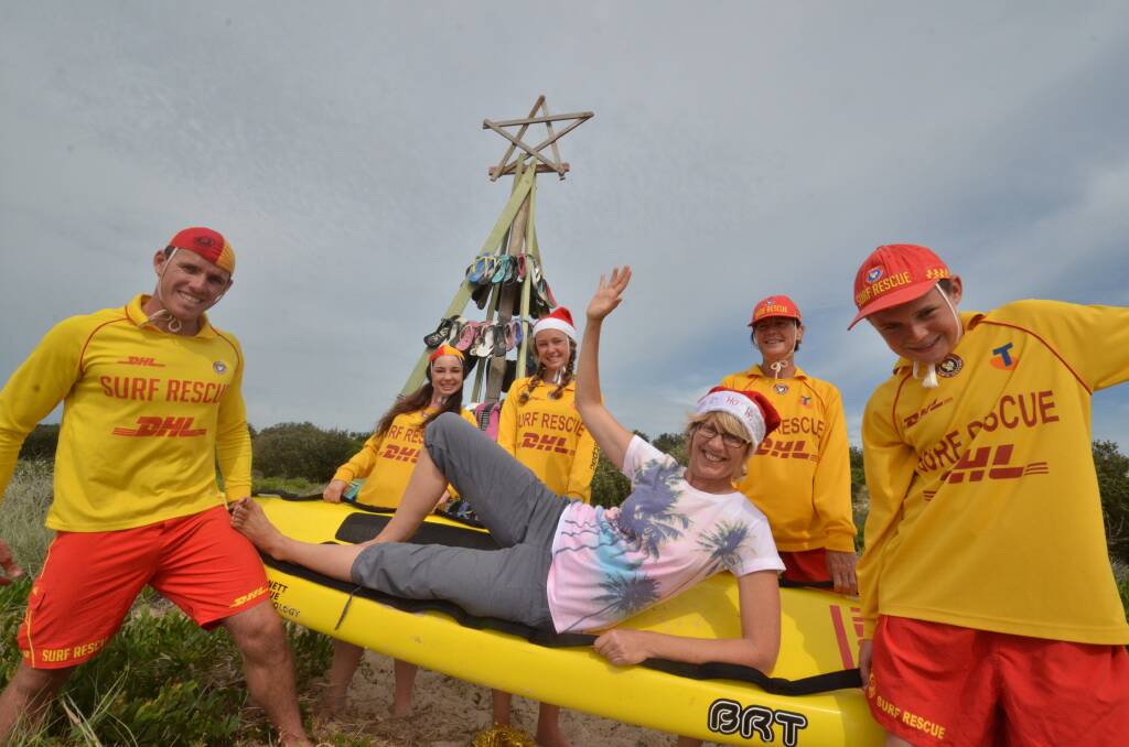 Christmas theme: Thong tree artist Mary Pavicich gets a welcome lift from Tacking Point Surf Life Saving Club active patrolling members Ryan Rosenbaum, Stephanie Clark, Jasmine Lawrence, Amanda Higgerson and Max Atherton.