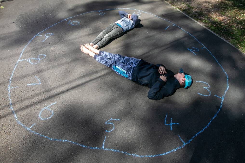 LOCKDOWN LEARNING: Thomas, 11, and Patrick, 8, Campbell learning to tell time on the driveway. Picture: Geoff Jones