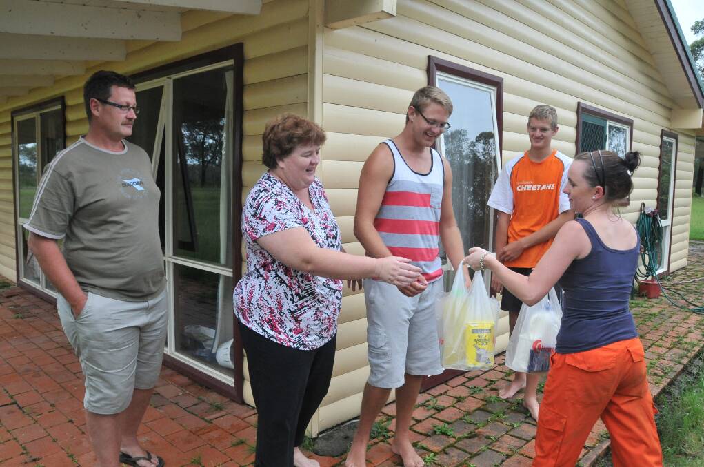 Ashley Bell from the SES supplies food parcels to the Coetzer family on the North Shore. Werner, Louise, Peter and Werner Jnr are thankful for the much needed supplies.
