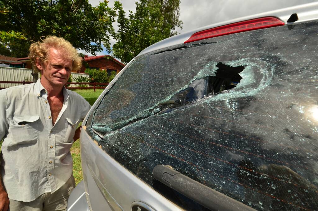 Not happy: Gordon Barnett and his car with smashed windows on Hastings River Drive.