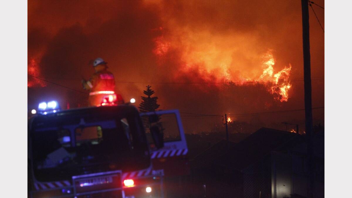 IN THE THICK OF IT: The huge blaze at Catherine Hill Bay surging towards fire crews.  Picture: Jonathan Carroll
