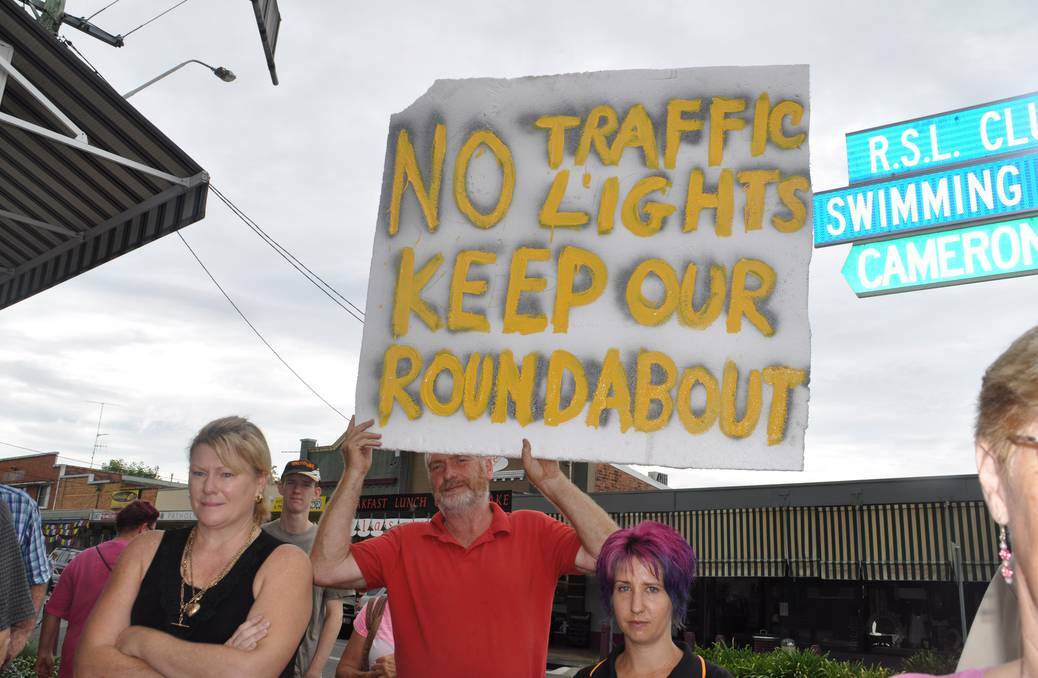 Graham Smith holding the placard protesting against the proposed traffic lights. pic: Wauchope Gazette